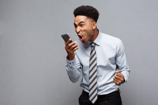 Business Concept - Stressful african american businessman shouting and screaming on mobile phone