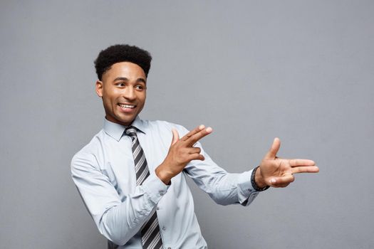 Business Concept - Cheerful happy young African American holding gun sign with fingers pointing to other