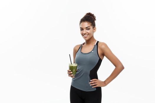 Healthy and Fitness concept - beautiful African American girl in sport clothes holding plastic water bottle after workout. Isolated on white studio background.