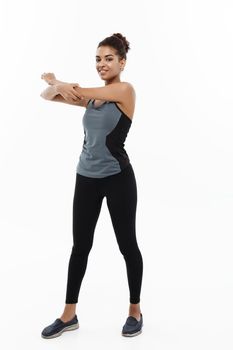 Sport, training, lifestyle and Fitness concept - Full-length portrait of beautiful happy African American woman stretching hands. Isolated on white studio background