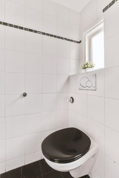 Modern toilet installed on beige wall under button and illuminated shelf in light restroom at home