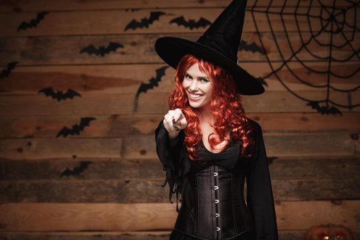 Halloween witch concept - Happy Halloween red hair Witch holding posing with magic wand over old wooden studio background