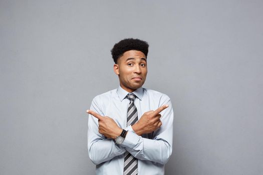 Business Concept - Confident thoughtful young African American pointing finger on side over grey background