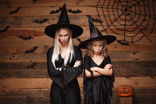 Halloween Concept - cheerful mother and her daughter in witch costumes disappointing with something