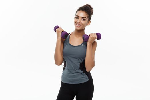 Healthy and Fitness concept - Beautiful American African lady in fitness clothes workout with dumbbell. Isolated on white background