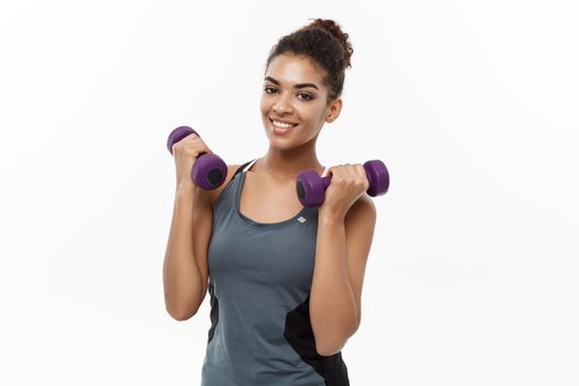 Healthy and Fitness concept - Beautiful American African lady in fitness clothes workout with dumbbell. Isolated on white background