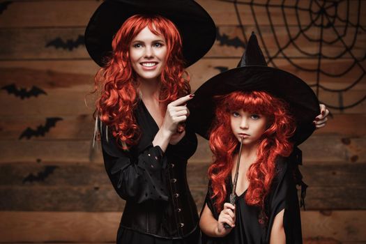 Halloween Concept - Beautiful caucasian mother dress up for her daughter in witch costumes and long curly hair ready for celebrating Halloween