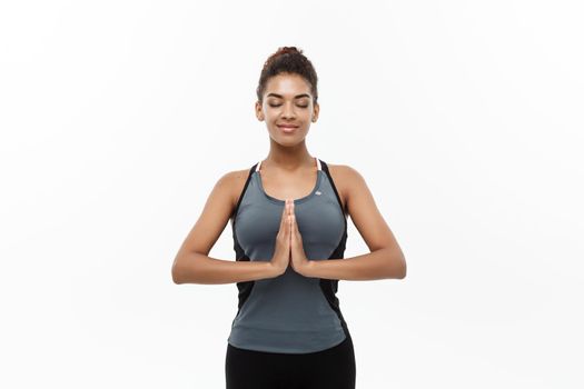 Healthy and Fitness concept - Beautiful American African lady in fitness clothing doing yoga and meditation. Isolated on white background