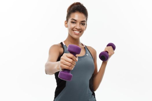 Healthy and Fitness concept - Beautiful American African lady in fitness clothes workout with dumbbell. Isolated on white background