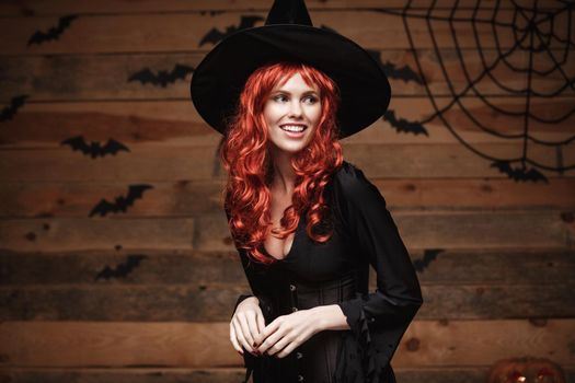 Halloween witch concept - Happy Halloween red hair Witch holding posing over old wooden studio background