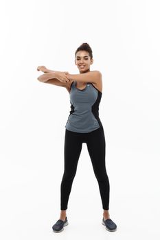 Sport, training, lifestyle and Fitness concept - Full-length portrait of beautiful happy African American woman stretching hands. Isolated on white studio background