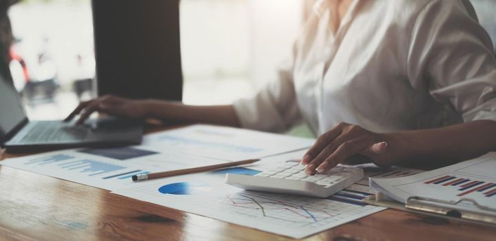 Asian female finance staff is calculating the investment results to deliver a report to his supervisor at the meeting. On the table in the office, the concept of calculating investment results.