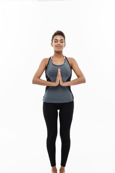 Healthy and Fitness concept - Beautiful American African lady in fitness clothing doing yoga and meditation. Isolated on white background