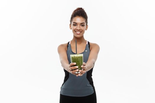 Healthy and Fitness concept - Beautiful American African lady in fitness clothing drinking healthy vegetable drink. Isolated on white background