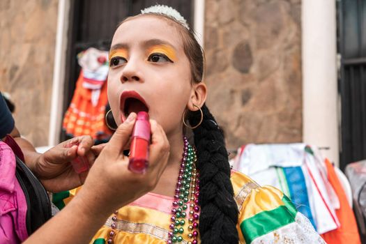Latina girl dressed in traditional Nicaraguan clothes being made up with lipstick