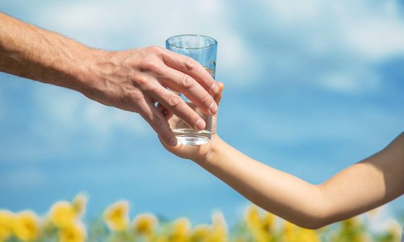 The child and father are holding a glass of water in their hands. Selective focus. Kid.