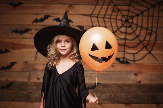 Halloween Witch concept - little caucasian witch child enjoy with halloween balloon. over bat and spider web background