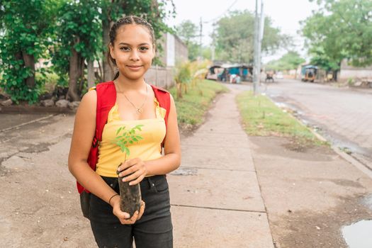 Portrait of a Latin girl holding a plant in a plastic bag watching the camera on a street in Leon Nicaragua