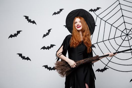 Halloween Concept - Happy elegant witch enjoy playing with broomstick halloween party over grey background