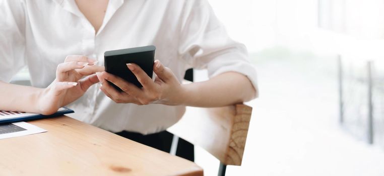 Close up hand of woman using smartphone at office.