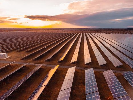 Aerial top view of a solar panels power plant. Photovoltaic solar panels at sunrise and sunset in countryside from above. Modern technology, climate care, earth saving, renewable energy concept