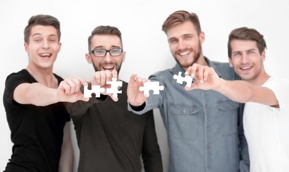 group of casual people holding white puzzles in hands on a gray background