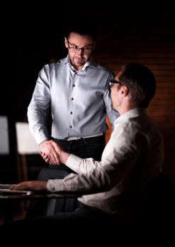 employees shaking hands near the desktop.the concept of teamwork