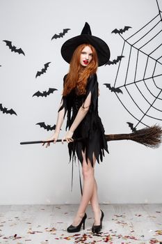 Halloween Concept - Happy elegant witch enjoy playing with broomstick halloween party over grey background