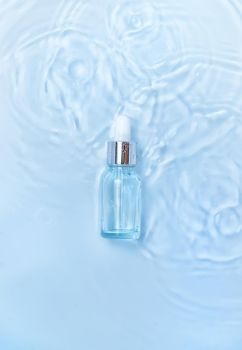 Cosmetics in a bottle in water, skin hydration concept. Hyaluronic acid. Selective focus. Nature.