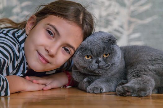 Child girl at home with a cat. Selective focus. Kid.