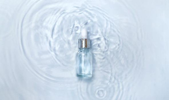 Cosmetics in a bottle in water, skin hydration concept. Hyaluronic acid. Selective focus. Nature.