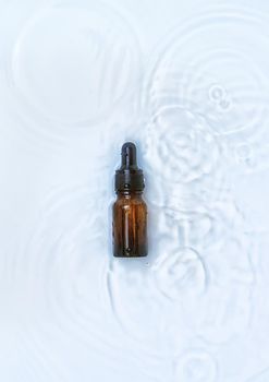 Cosmetics in a bottle in water, skin hydration concept. Hyaluronic acid. Selective focus. Nature.