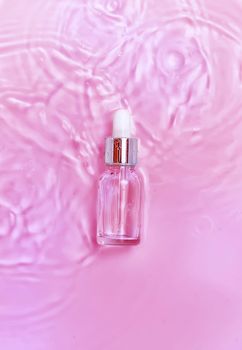 Cosmetics in a bottle in water, skin hydration concept. Hyaluronic acid. Selective focus. Nature.