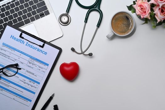 Top view laptop, stethoscope, medical report and heart on white table. Cardiology, healthcare and medical concept.
