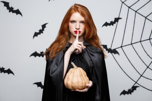 Portrait of beautiful caucasian witch holding pumpkin for celebrating Halloween
