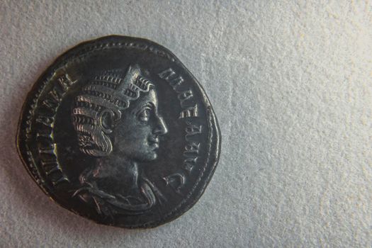 old roman coin on white paper closeup