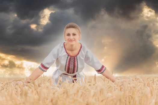 girl in an embroidered shirt on a wheat field and a sunset sky