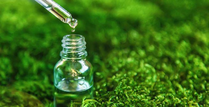 Cosmetics in a bottle and essential oils on moss. Natural spa. Selective focus. Nature.