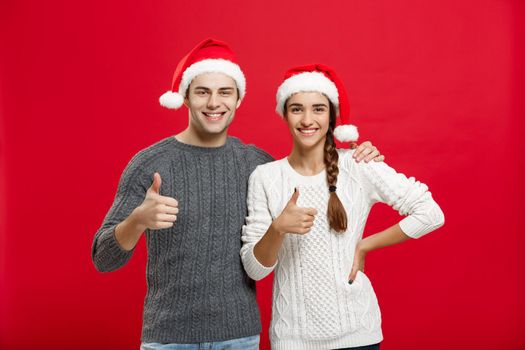 Christmas Concept - portrait lovely young couple showing thump up gesture with finger to camera.