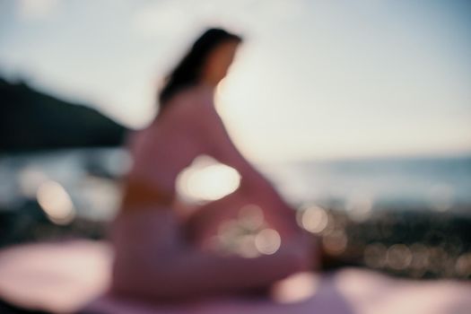 Young woman with black hair, fitness instructor in pink sports leggings and tops, doing pilates on yoga mat with magic pilates ring by the sea on the beach. Female fitness daily yoga concept