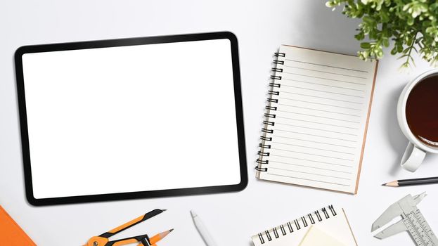 Mockup digital tablet, coffee cup, stationery and potted plant on white table. Top view.
