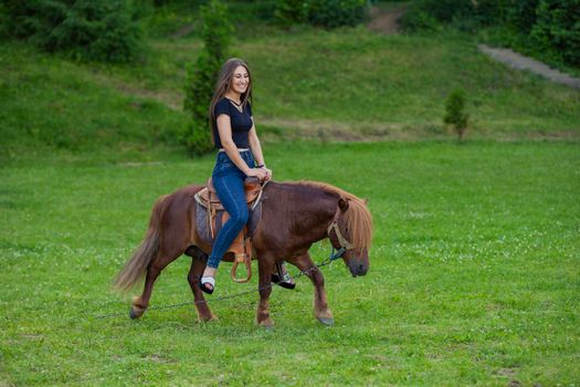 girl riding a pony on a green lawn