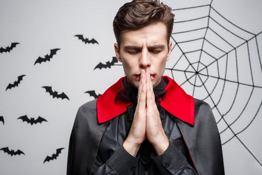 Vampire Halloween Concept - Portrait of handsome caucasian in Vampire halloween costume praying
