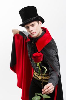 Vampire Halloween Concept - Portrait of handsome caucasian Vampire holding red beautiful rose