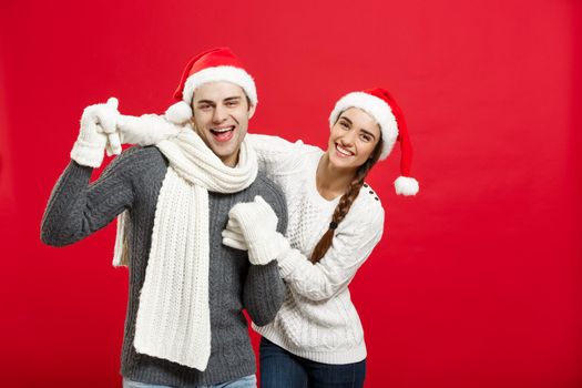 Christmas concept - Happy young couple in sweatesr celebrating christmas with playing and dancing.