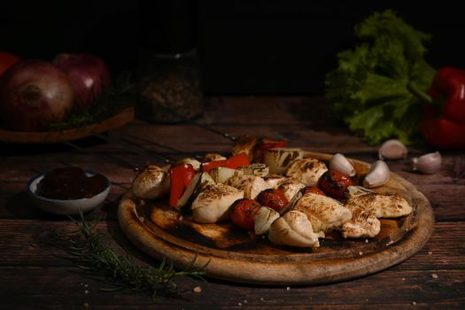 Delicious chicken shish kebab skewer barbecue with vegetables and spices and barbecue sauce on wooden cutting board.