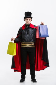Vampire Halloween Concept - Happy handsome caucasian Vampire holding colorful shopping bag on white background