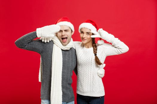 Portrait of a happy young couple posing over red studio background.