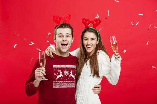Christmas Concept - Happy caucasian man and woman in reindeer hats celebrating christmas toasting with champagne flutes, congratulating on xmas.
