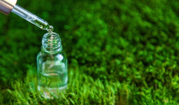 Cosmetics in a bottle and essential oils on moss. Natural spa. Selective focus. Nature.